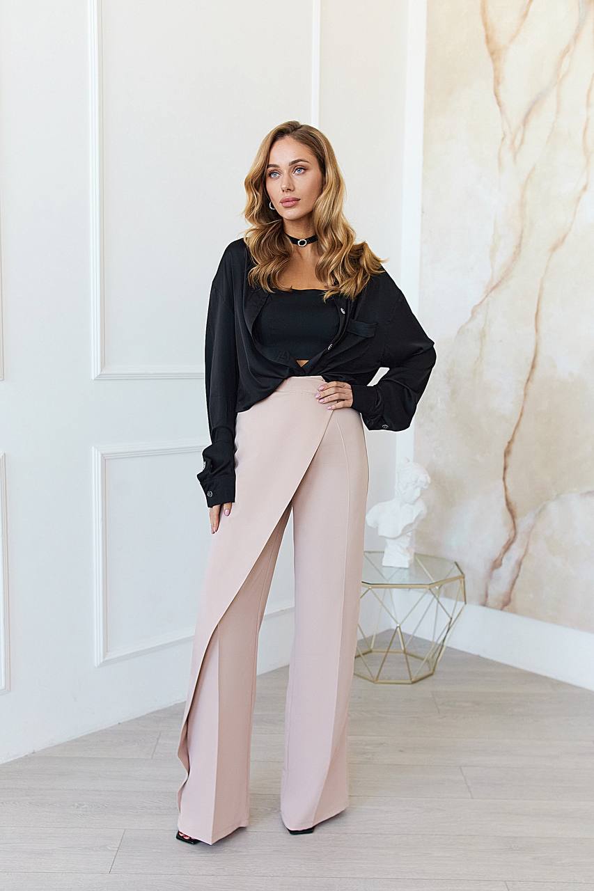Woman wearing a black top and pink pants in a stylish interior setting