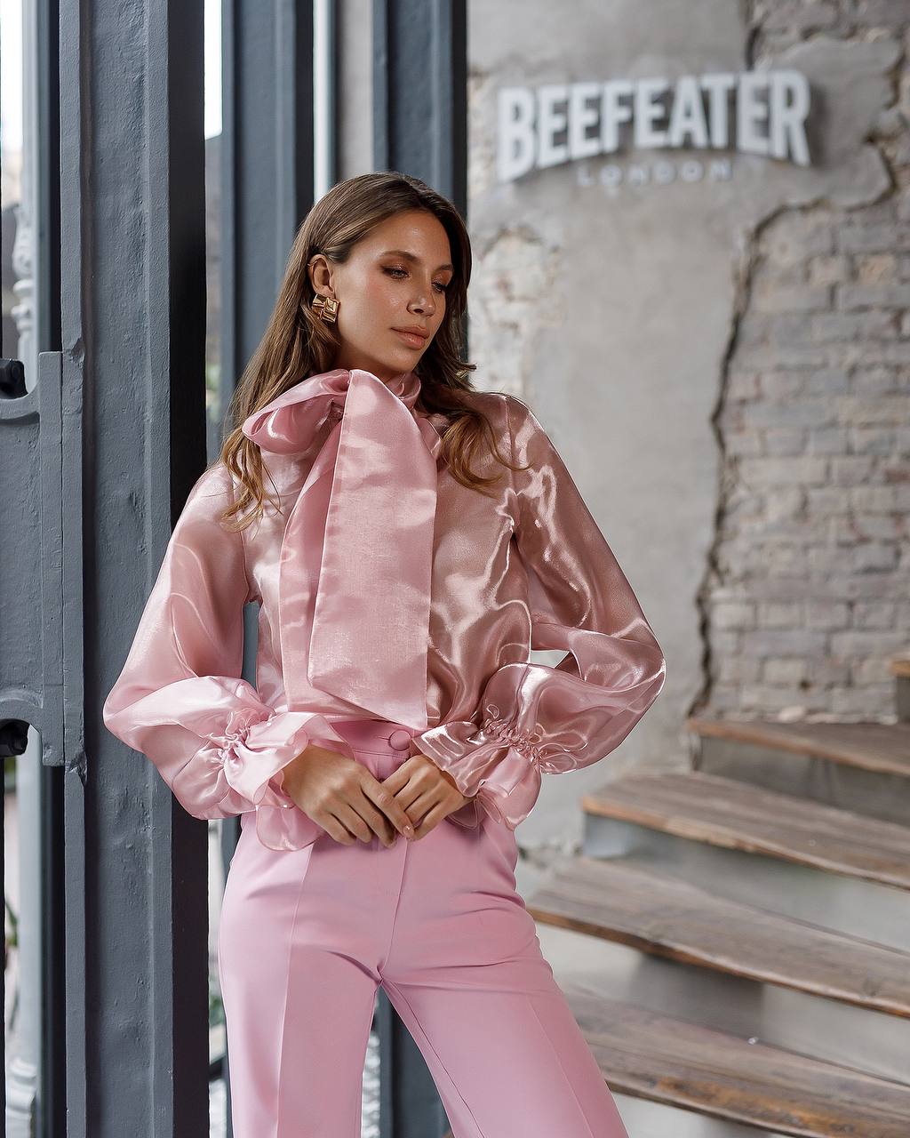 Woman in a pink outfit standing in front of a 'Beefeater London' sign.