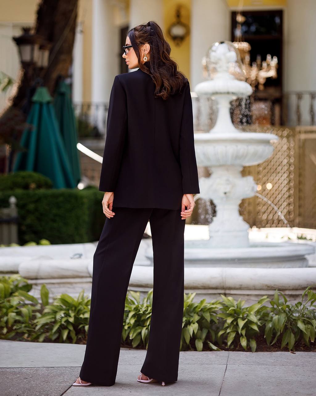 Woman in a black suit standing in front of a fountain