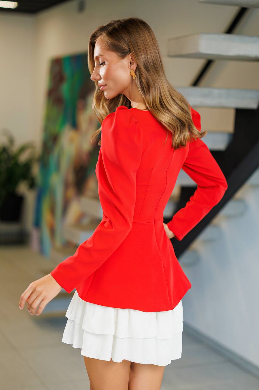 Woman wearing a red blazer and white skirt in an indoor setting
