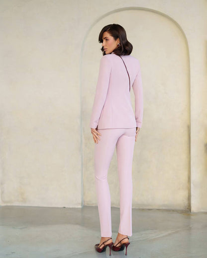 Woman in a light pink suit standing in a minimalistic room with a white archway.