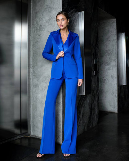 Woman wearing a blue suit standing against a dark background