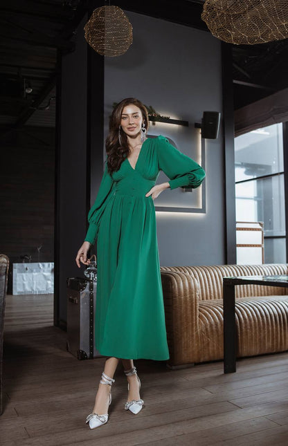 Woman in a green dress standing in a modern interior setting