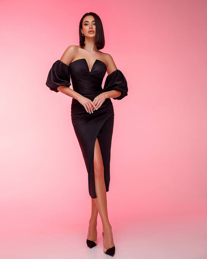 Woman wearing a black dress with puffed sleeves against a pink background