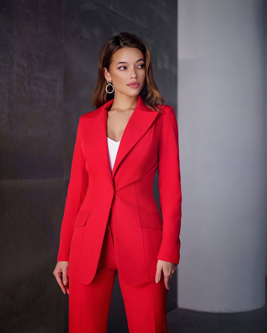 Woman wearing a red suit against a gray background