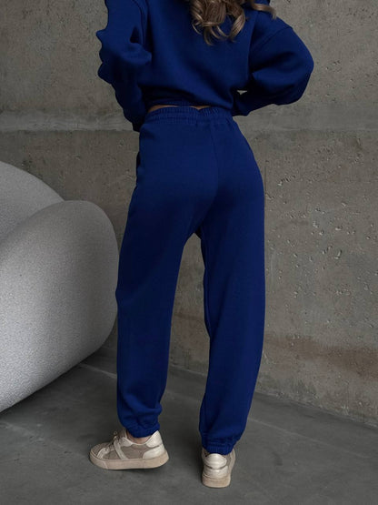 Person wearing a blue tracksuit standing against a concrete wall.