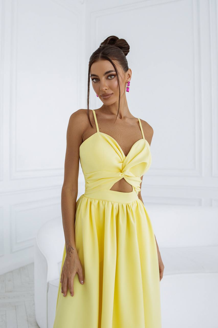 Woman wearing a yellow dress with cut-out design against a white background