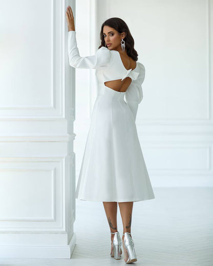 Woman wearing a white dress with cut-out design in a minimalistic setting
