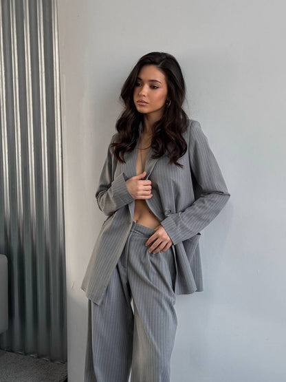 Woman wearing a gray outfit against a plain background