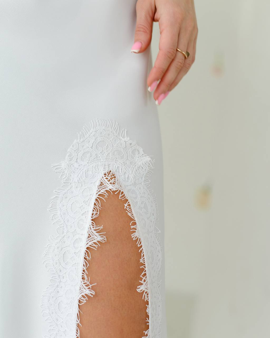 Close-up of a white lace dress with a cutout design, held by a hand.