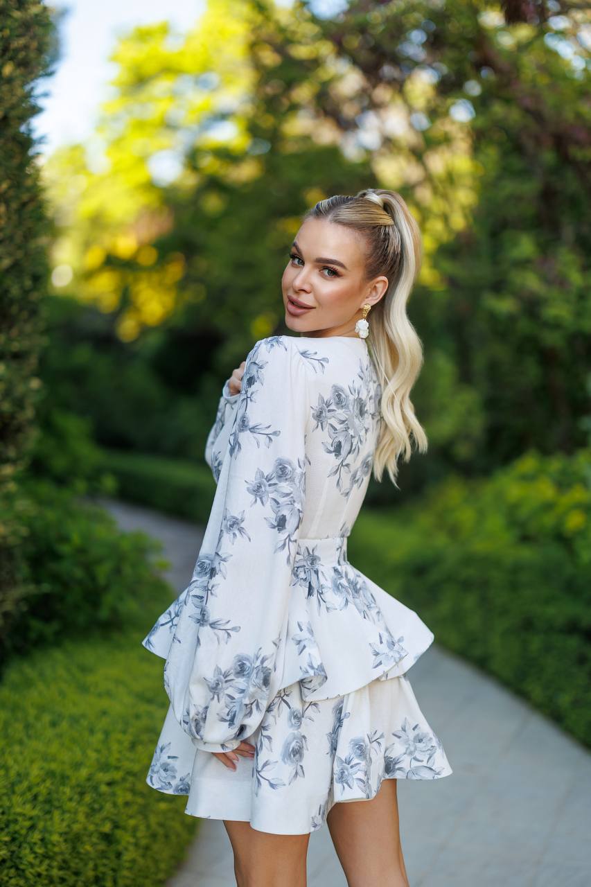 Woman in a floral dress standing outdoors with greenery in the background