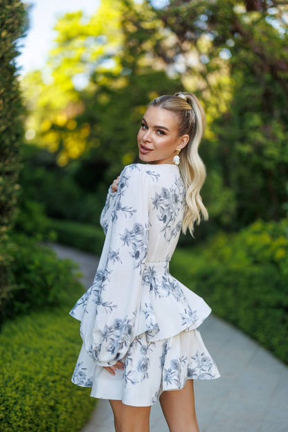 Woman in a floral dress standing outdoors with greenery in the background