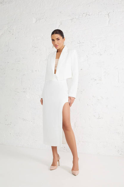 Woman wearing a white dress with a deep neckline and slit on a white background