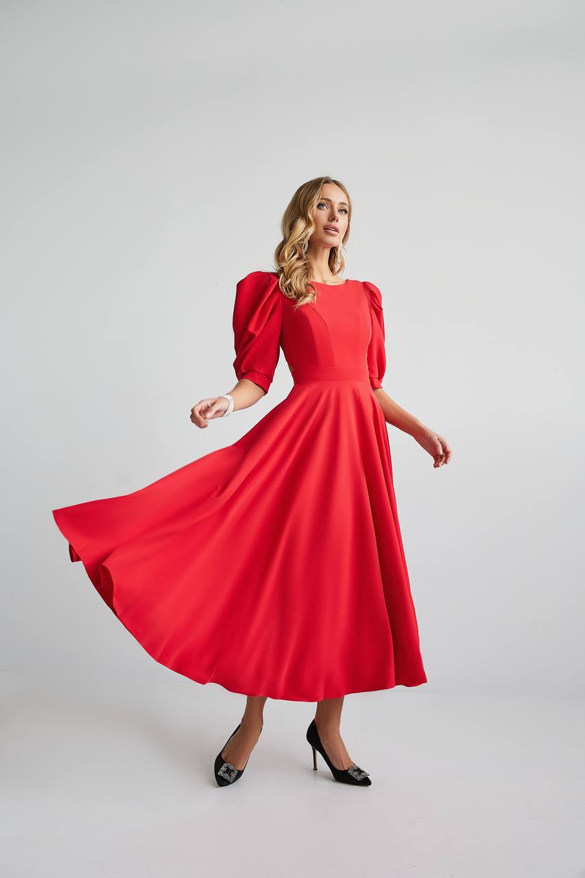 Woman wearing a red dress with puff sleeves on a plain background