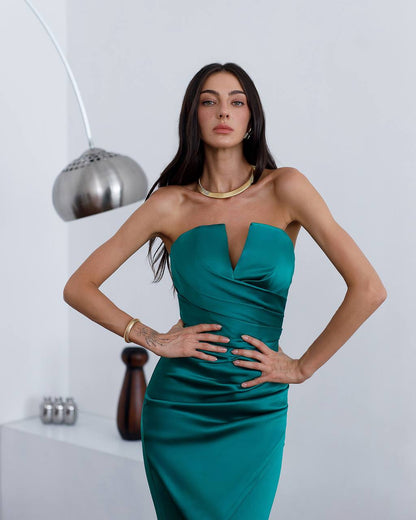 Woman wearing a teal strapless dress against a white background