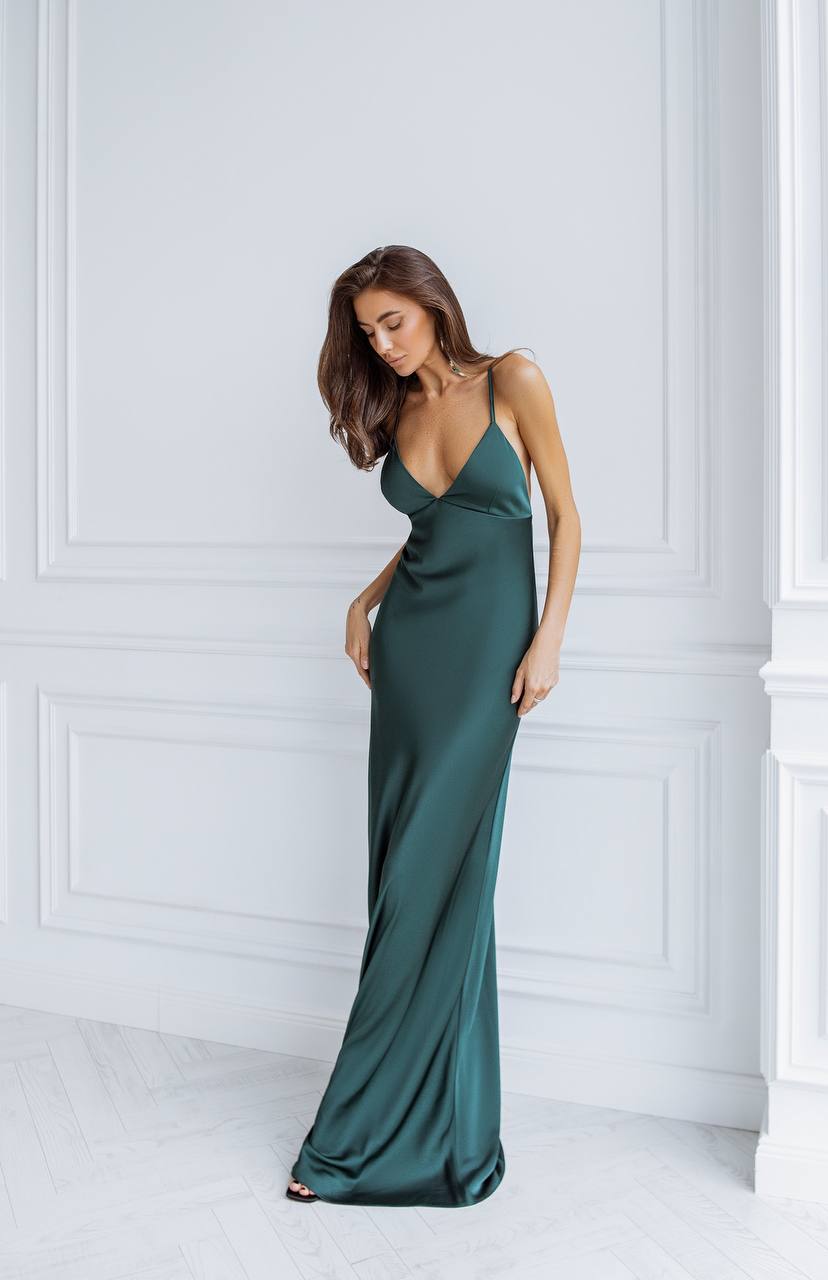 Woman wearing a long green dress against a white wall