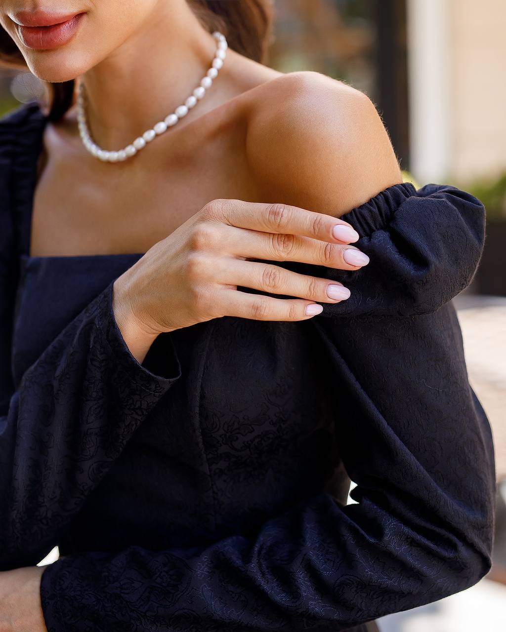 Woman wearing a black off-shoulder top with a blurred background