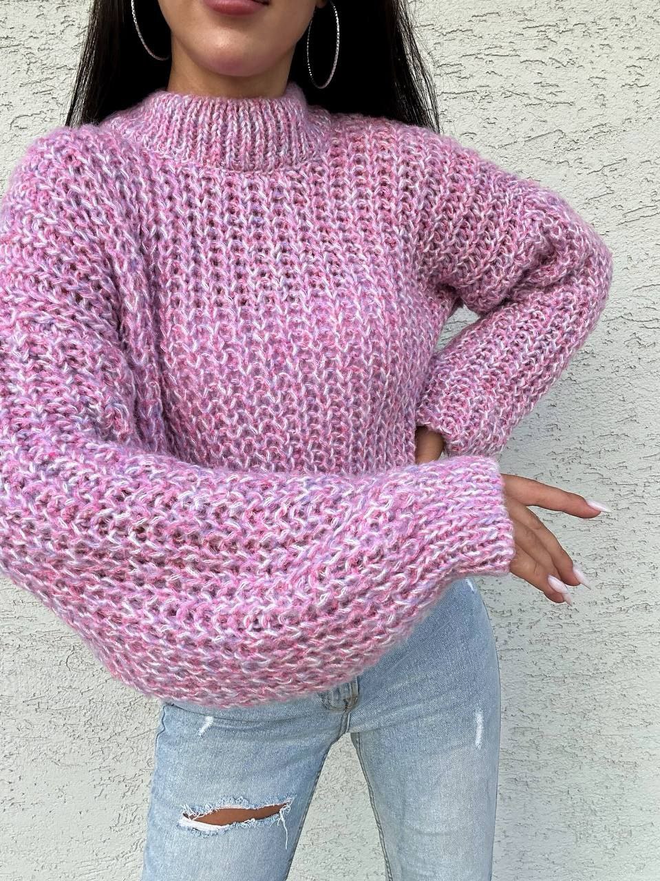 Person wearing a pink knitted sweater against a light gray background