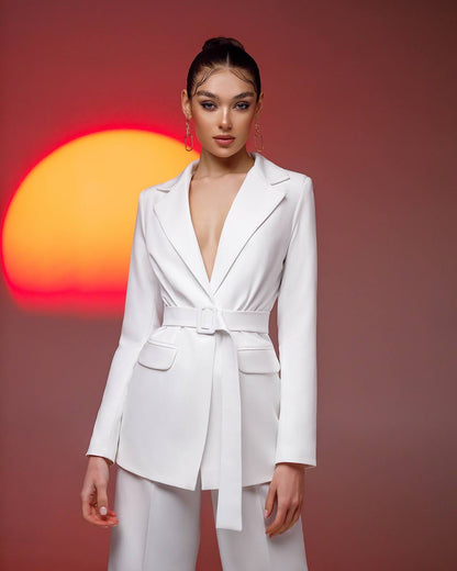 Woman wearing a white blazer and pants with a sunset background