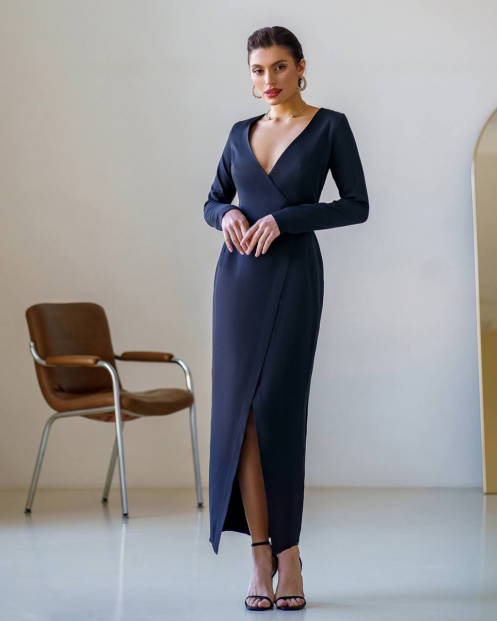 Woman wearing a long black dress with a chair in the background