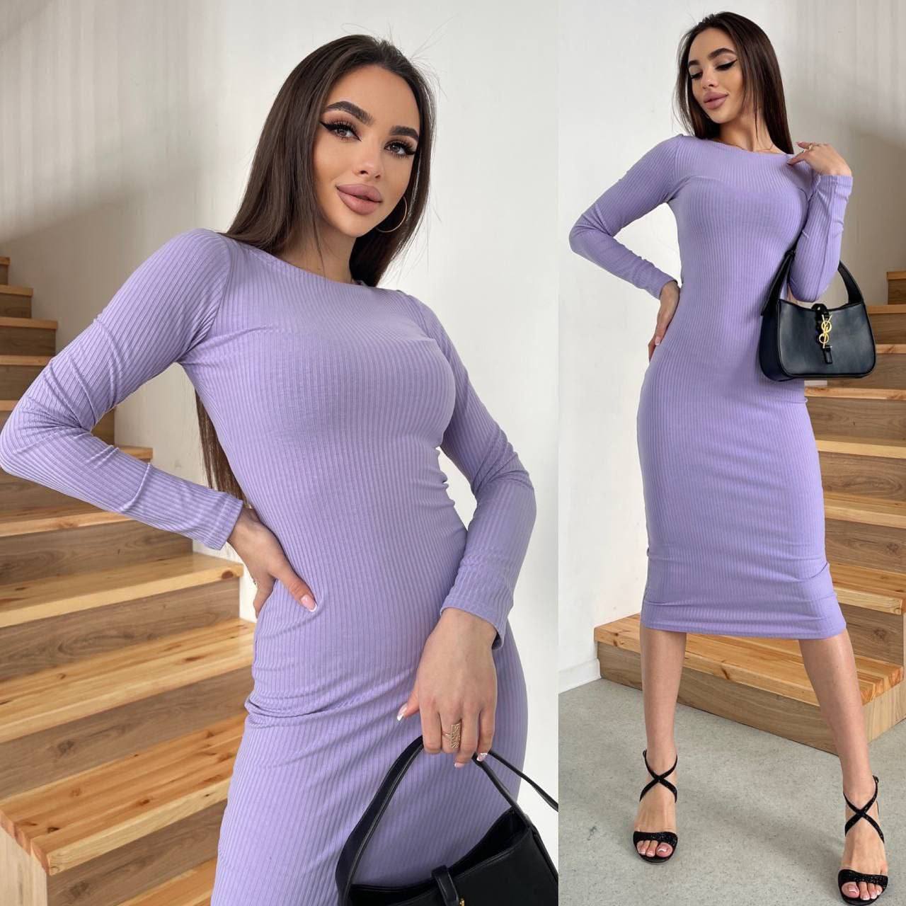 Woman wearing a purple dress with long sleeves, standing on wooden stairs.