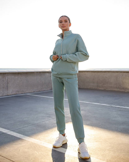 Person wearing a light green tracksuit on a rooftop.