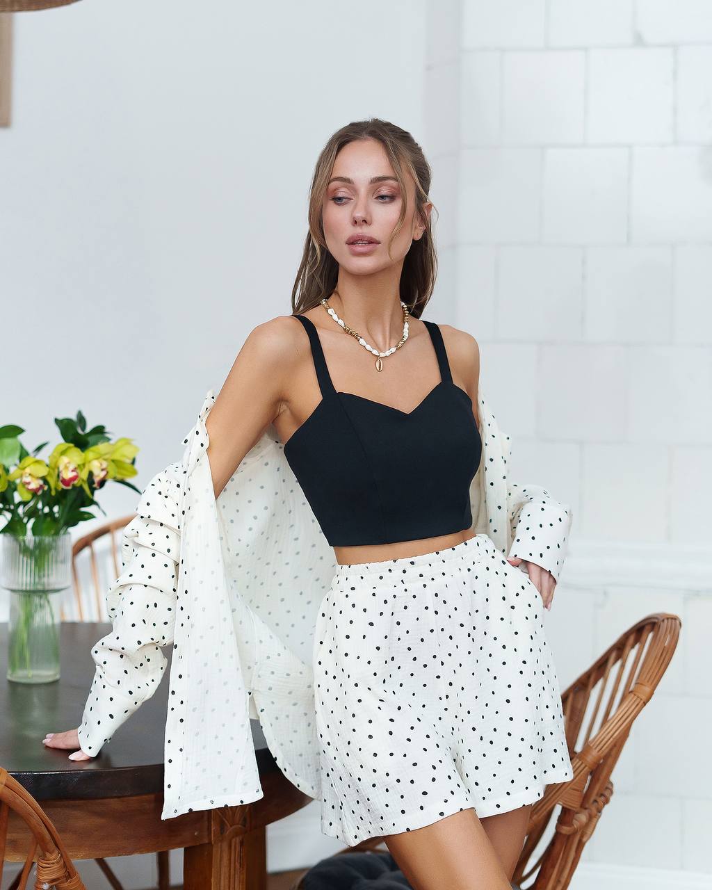 Woman wearing a black top and white polka dot skirt in a casual setting.