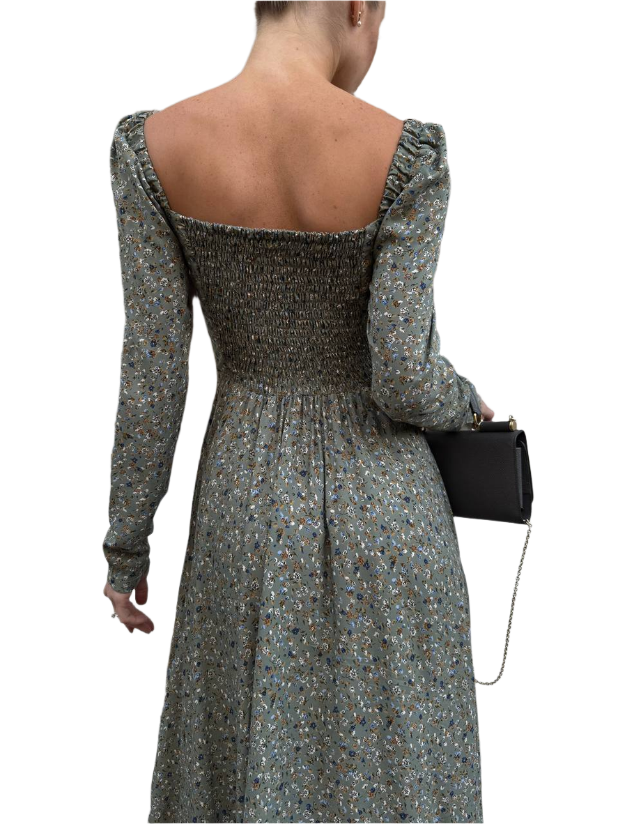 Woman wearing a floral dress with long sleeves and a black clutch on a white background