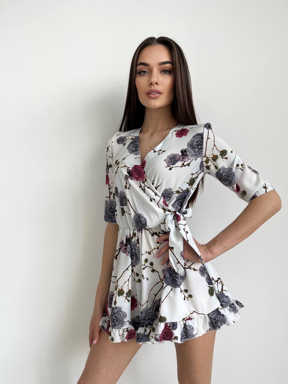 Woman wearing a floral dress against a plain background