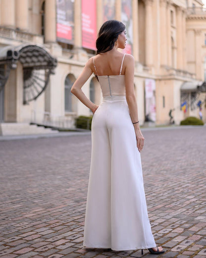 Woman in a white jumpsuit standing on a city street.