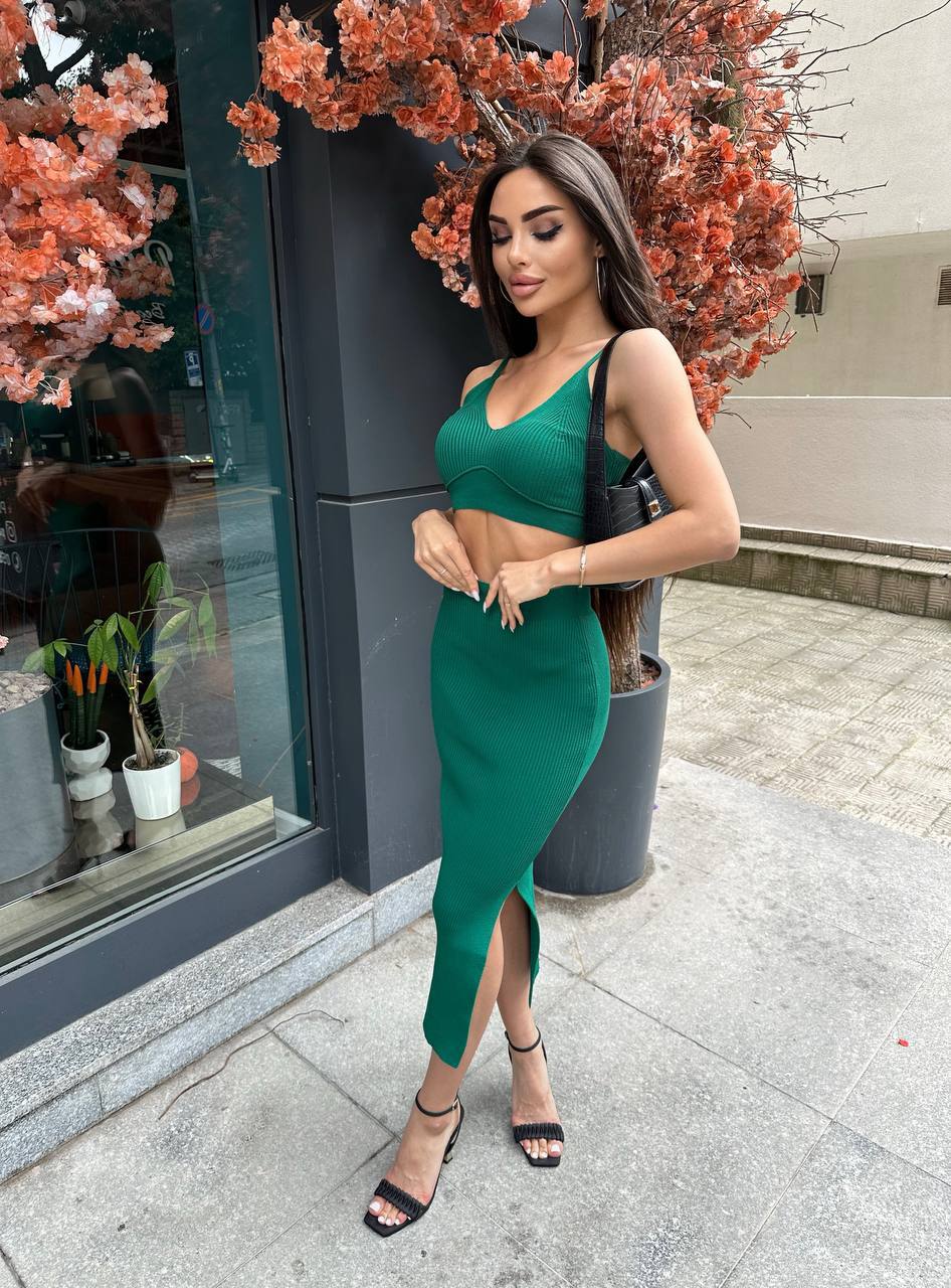 Woman in a green dress standing outdoors with decorative plants in the background