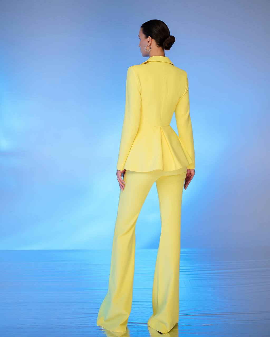 Person wearing a bright yellow suit standing against a blue gradient background