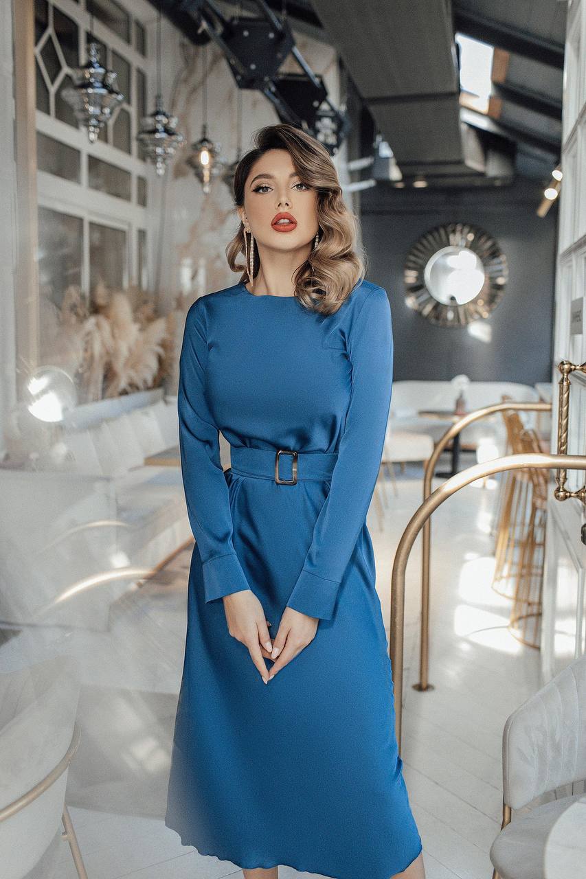 Woman in a blue dress standing in an elegant interior setting
