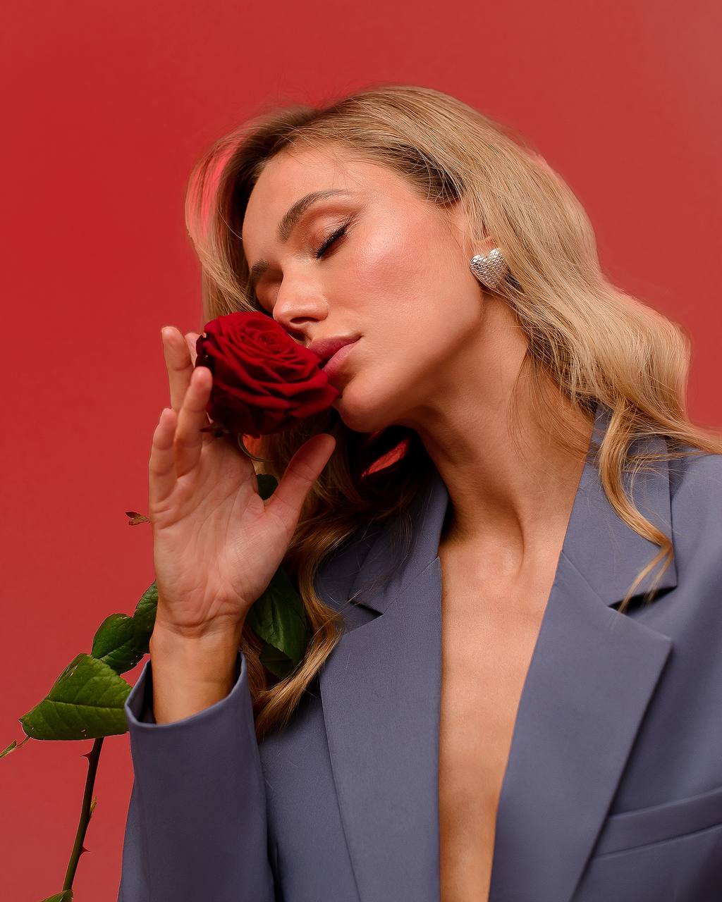 Woman holding a red rose against a red background