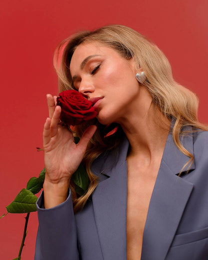 Woman holding a red rose against a red background