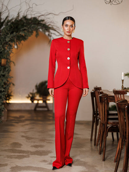Woman in a red suit standing in a room with a dining table and chairs.