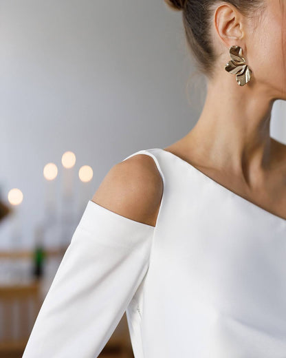Woman wearing a white off-shoulder top with a blurred background