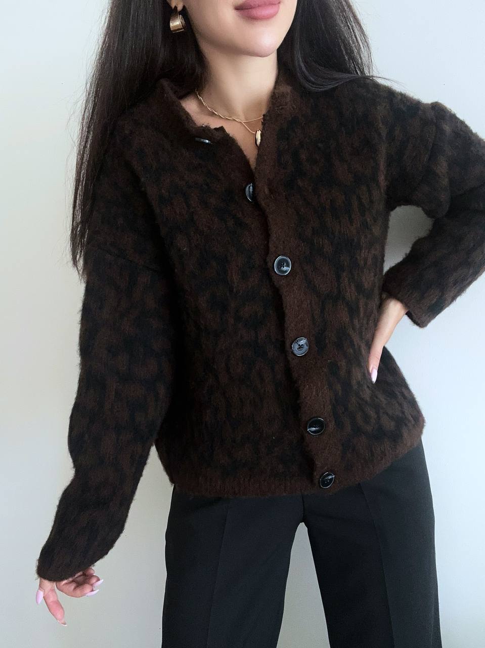Person wearing a brown patterned cardigan against a white background