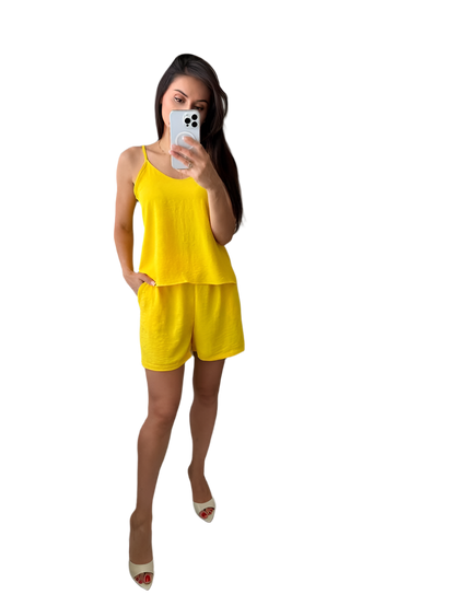 Woman taking a selfie wearing a yellow outfit on a white background