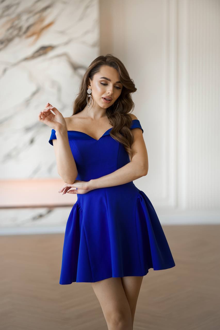 Woman wearing a blue off-shoulder dress in an indoor setting