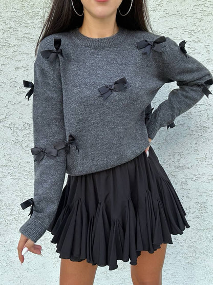 Gray sweater with black bows and a black skirt on a textured light gray background