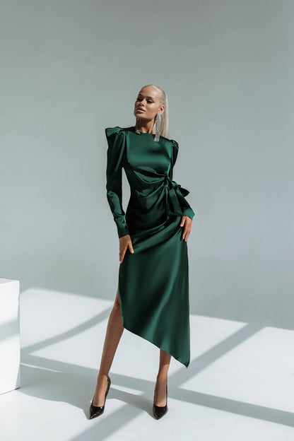 Woman wearing a green dress with a high slit on a white background