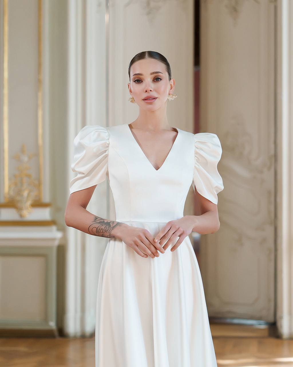 Woman wearing a white dress with puffed sleeves in an elegant interior setting