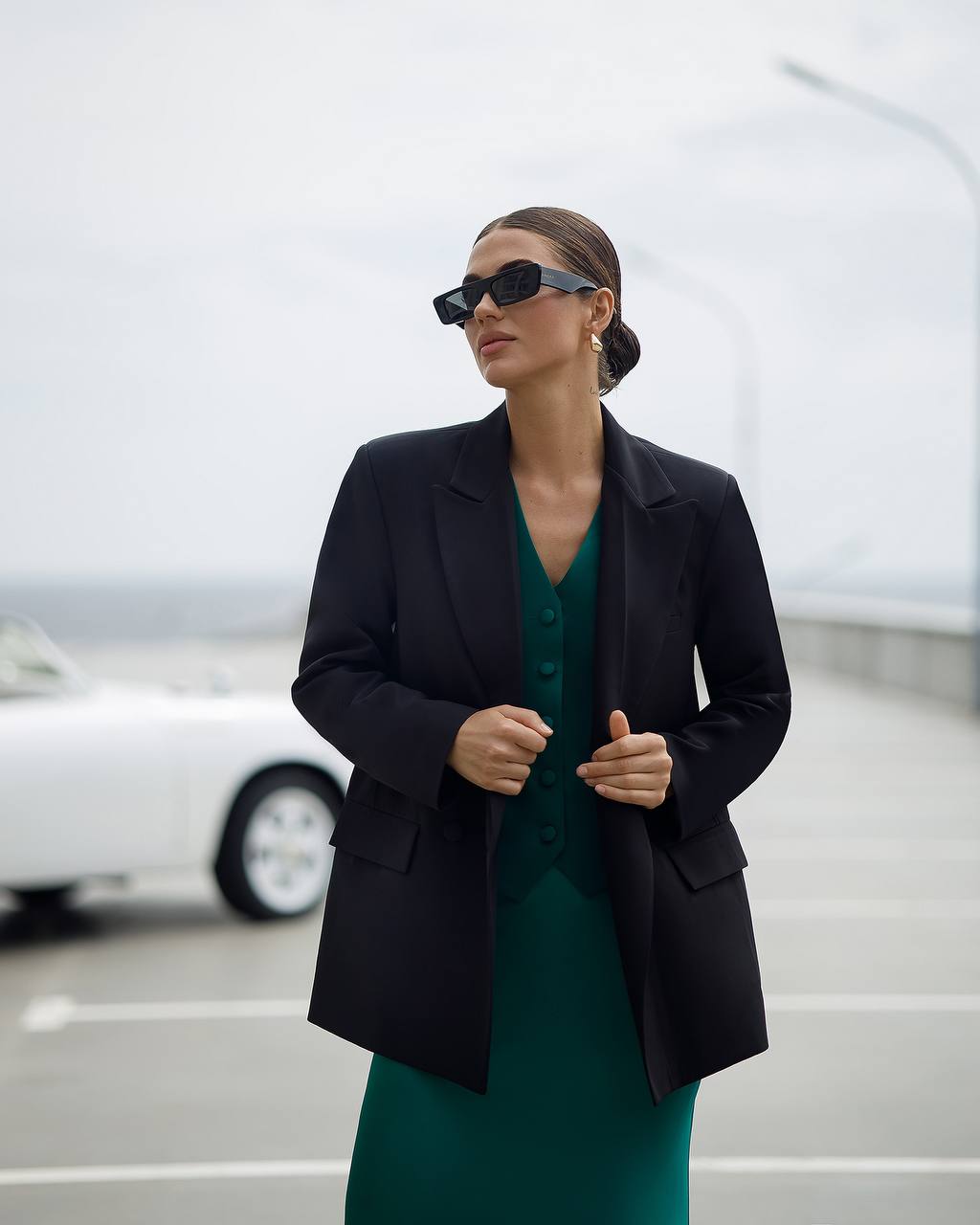 Woman wearing a black blazer over a green dress in an outdoor setting