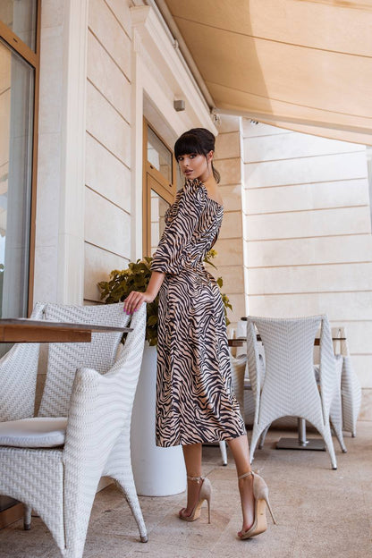 Woman in a zebra print dress standing in an outdoor setting with white chairs and tables.