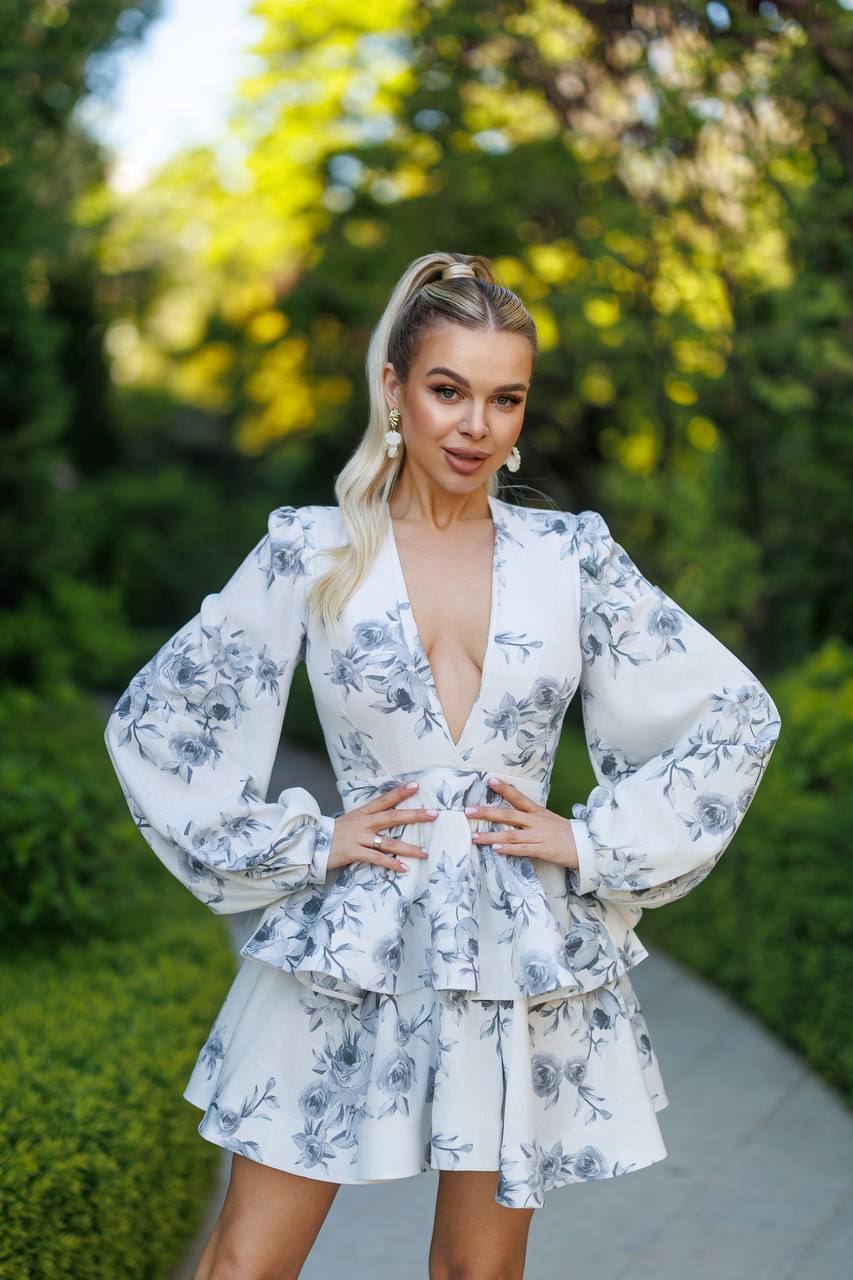Woman wearing a floral dress standing outdoors with greenery in the background