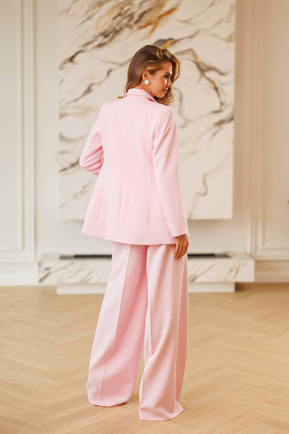 Woman in a pink outfit standing in a room with marble walls.