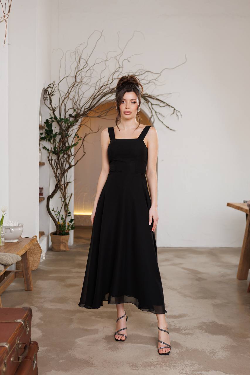 Woman in a black dress standing in a room with minimal decor