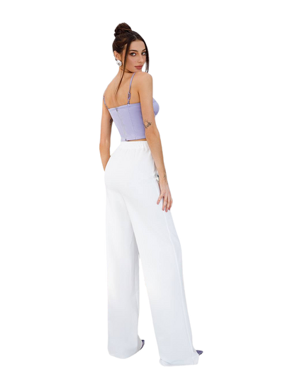 Woman wearing a purple top and white pants on a white background