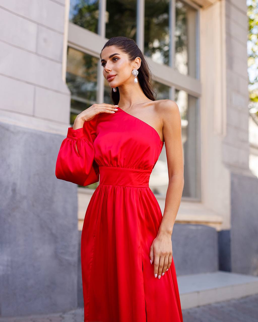 Woman wearing a red one-shoulder dress standing outdoors.
